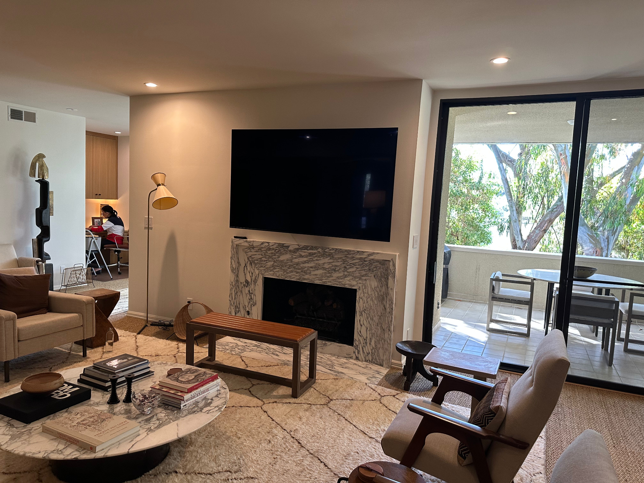 Large television installed in a living room above a marble fireplace